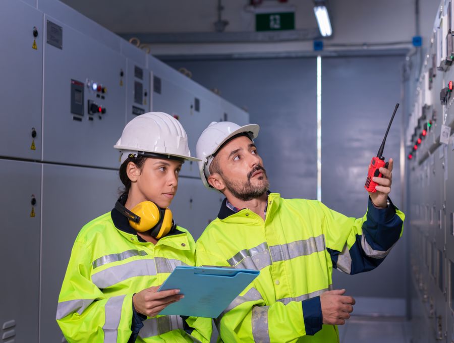 Two electricians inspecting a switch room