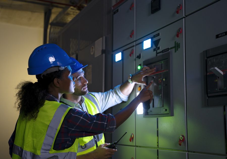 Technicians inspecting an electrical control cabinet